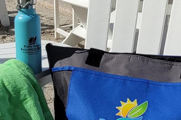 Beach bag, water bottle, and towel on adirondack chair on the back