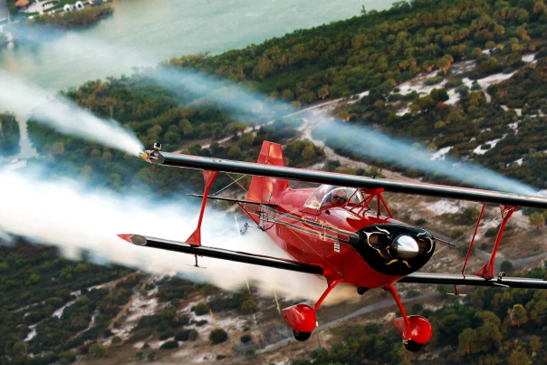 Close up of small red airplane trailing smoke