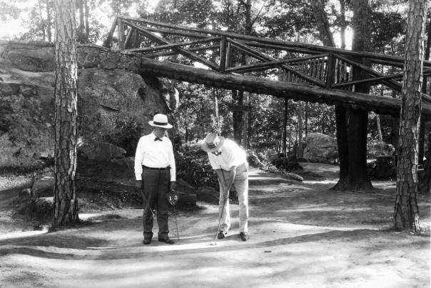 Two men play tom Thumb golf in historic black and white photo at rock city