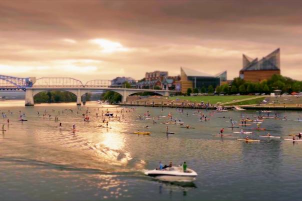 People on Kayaks and paddleboards pepper the Tennessee River with Chattanooga bridges and downtown riverfront in the background