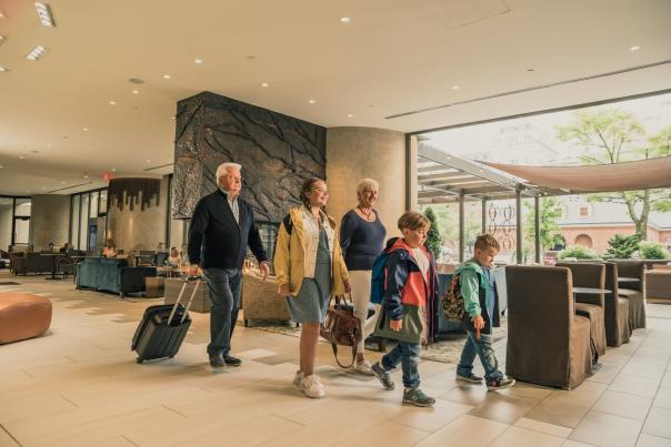 family walks through hotel lobby with suitcases