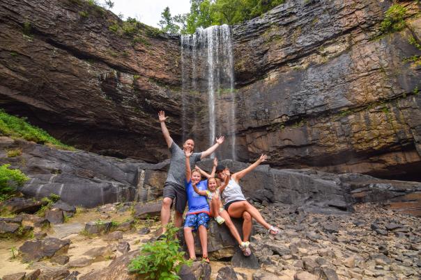 family poses for photo in front of waterfall