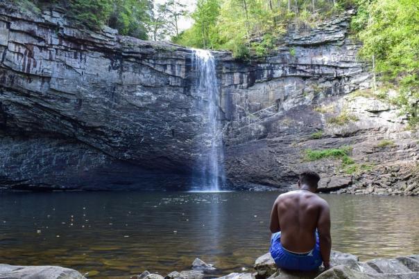 Man sits in front of waterfall