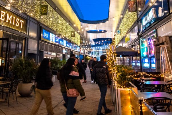 People walking through The Brewery Quarter in Cheltenham during the evening.