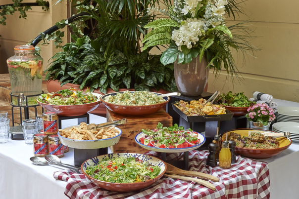 Images shows a display of summer food dishes with a plant and flower display at the back