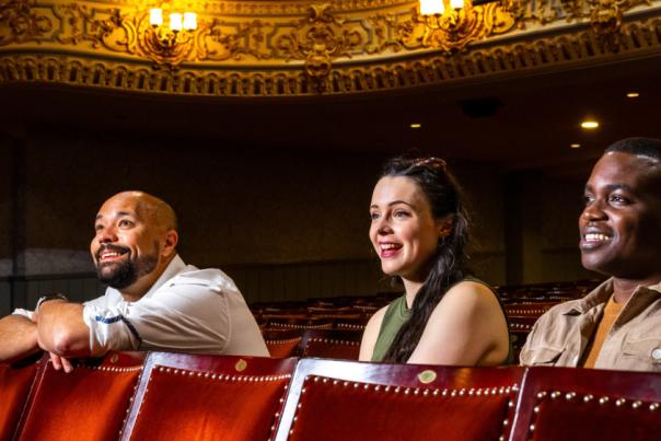 Three people sat watching a performance at the Everyman Theatre Cheltenham.
