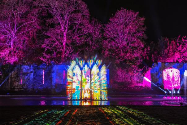 Visual light show projected onto the water fountains and long pond in front of the Tithe Barn at Sudeley Castle, Gloucestershire.