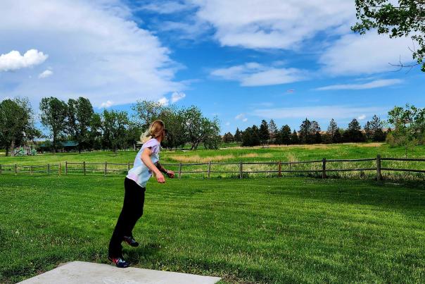 Cheyenne local, Brie, throws a driver disc down field at Clear Creek Disc Golf Course