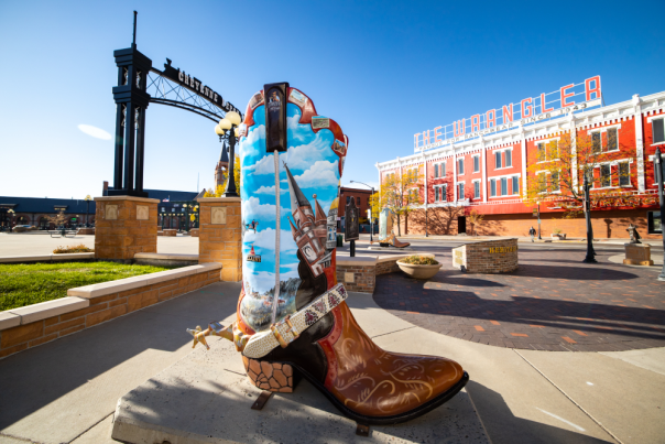 A vibrant boot sculpture in downtown Cheyenne under the Cheyenne Depot arch with historic buildings in the background, capturing top historic things to do.