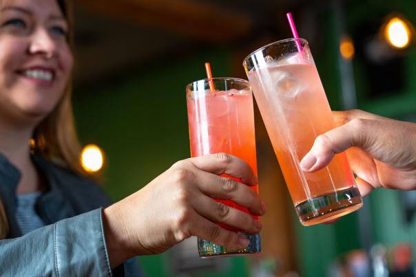 Two people making a toast with refreshing summer drinks at a lively Cheyenne bar.