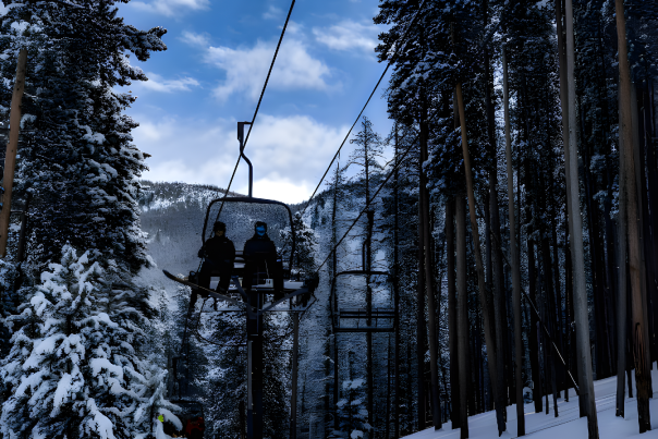 Two skiers ride a ski lift up a snowy mountain at the Snowy Range Ski Resort.