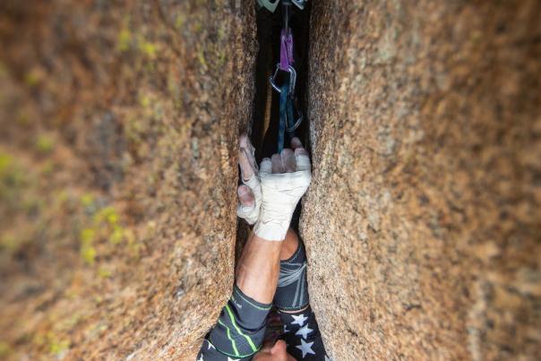 Climber navigating a crack at Vedauwoo using a hand-jamming technique with a protection cam in place, showcasing Wyoming rock climbing.