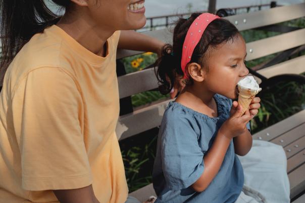 Little Girl Eats Ice Cream Next to her Mom