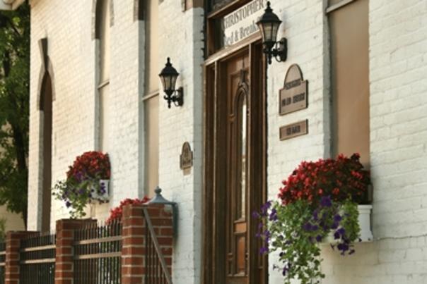 Gray steps lead up to the wooden front door of a white brick church that is now Christopher's B&B in Bellevue KY