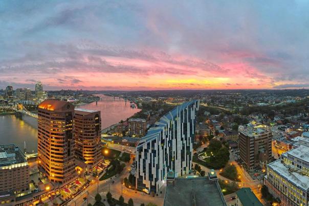 The sky glowing pink and gold with a sunrise behind the skyline of Covington, Ky. with Cincinnati, Ohio in the background