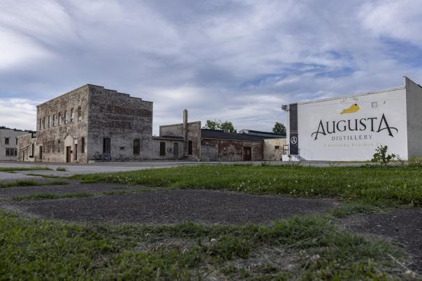 The exterior of Augusta Distillery includes a white brick building with the brand's logo, as well as an adjoining historic brick structure