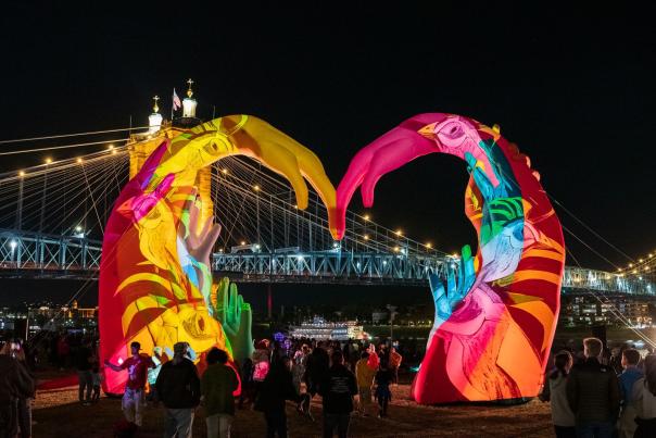 A colorful illuminated heart sculpture frames the Roebling Bridge