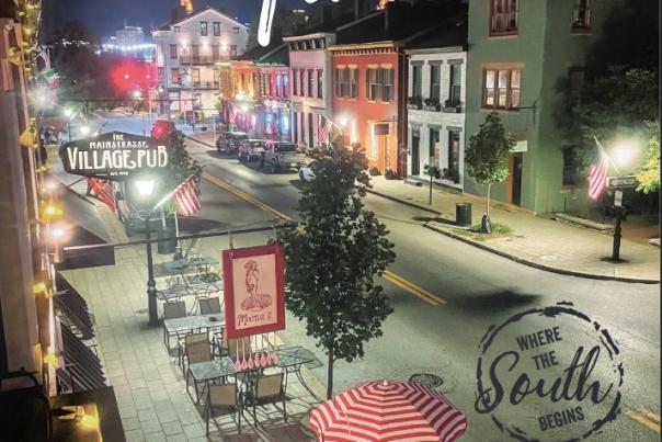 This magazine cover shot features a photo of Mainstrasse at night, with red striped umbrellas and cafe tables set up along the sidewalk