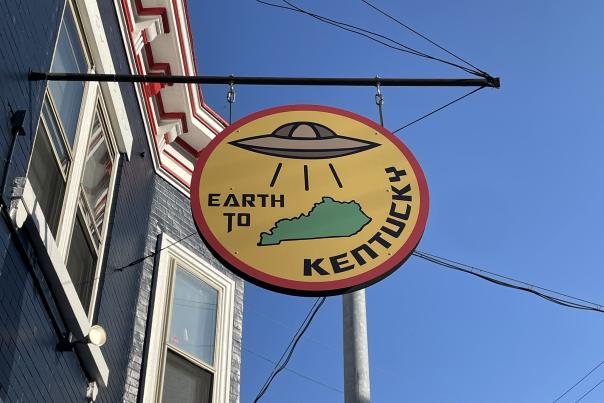 Image is of the over hanging "Earth to Kentucky" sign which is circular and has a UFO on it.