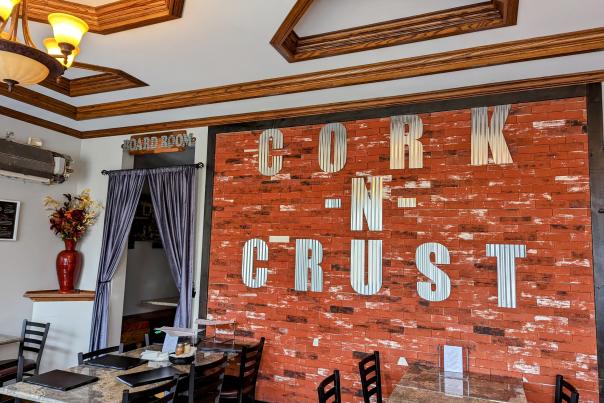 Brick wall featuring metal letters that spell out Cork N Crust