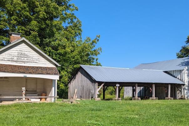 Image is of the Milk House and Wagon Shed during the day in summer.
