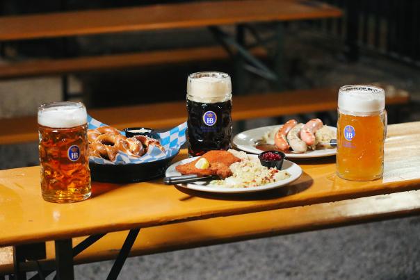 A bench laden with three steins of beer and plates of pretzels, schnitzel, and wursts at Hofbrauhaus in Newport, Ky.
