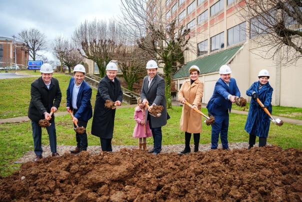 officials use shovels to dig into dirt at groundbreaking ceremony