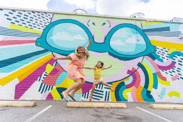 Mother and daughter jumping in front of a mural