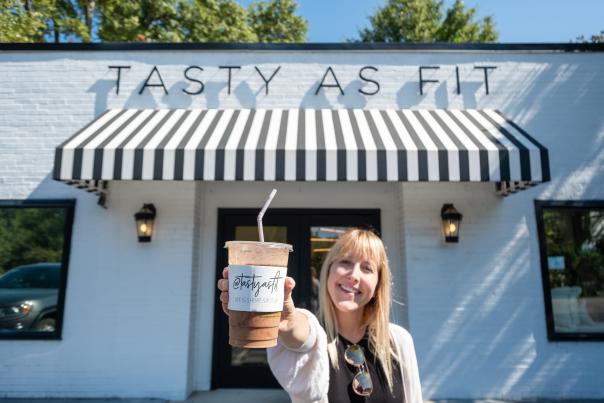 Woman holding out a smoothie in front of Tasty As Fit