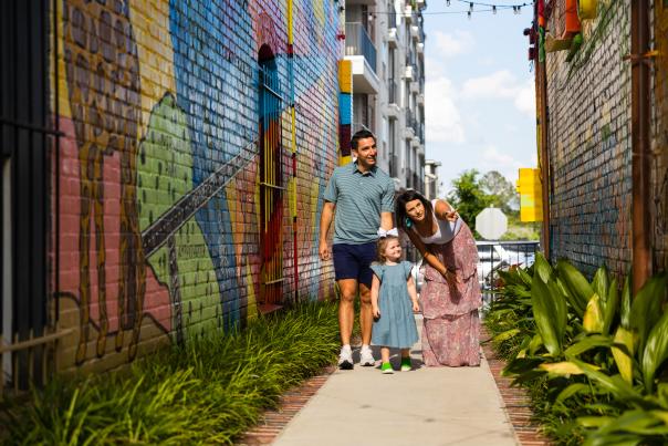 Family of three looks at a brightly colored mural