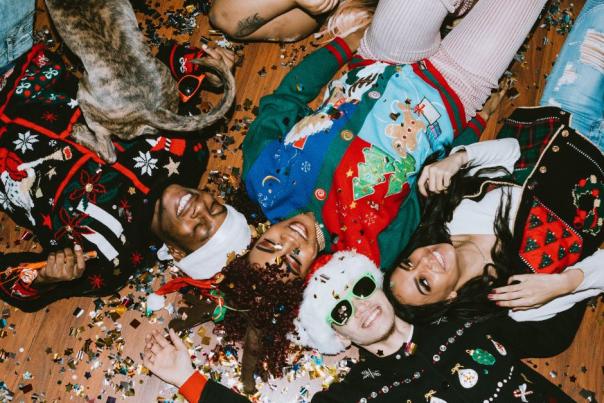 Group of people wearing Holiday sweaters celebrating