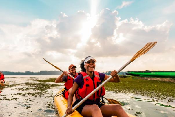 Couple kayaking in lake with sun coming through clouds