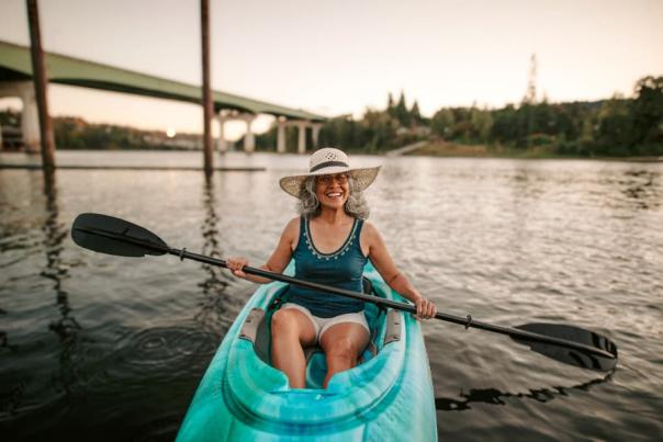 Person in kayak with hat smiling near bridge