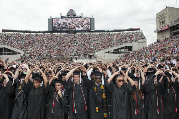 OSU graduates hold up arms in 'o' shape at graduation