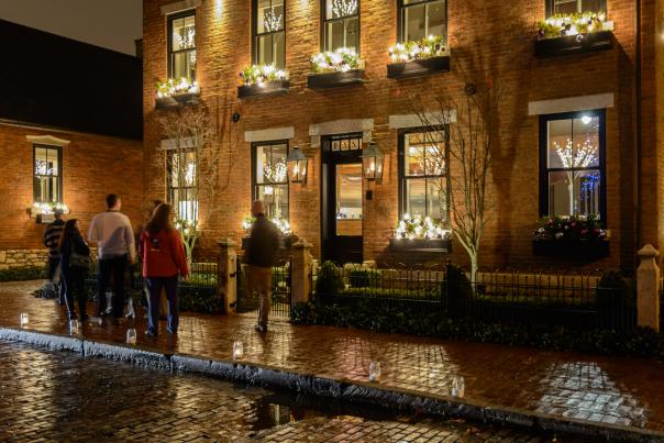 Columbus visitors walking in front of brick house in German Village lit for holidays