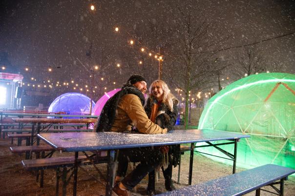 Man and woman enjoying snow and outdoor igloos at Land-Grant Brewing Co.