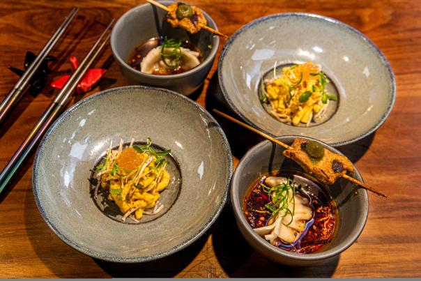 Various sized bowls full of colorful food sit on a wooden table