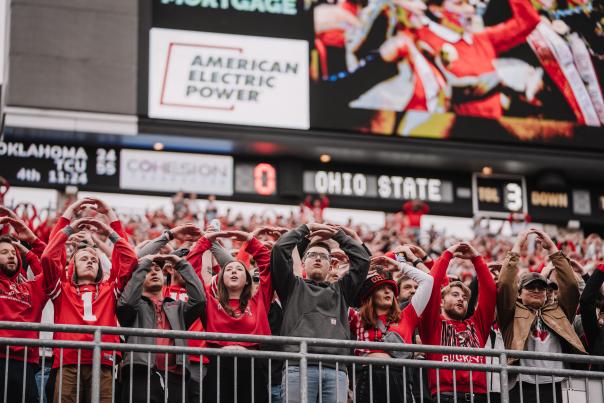 Crowd of OSU students holds hands above their head to form an "O"
