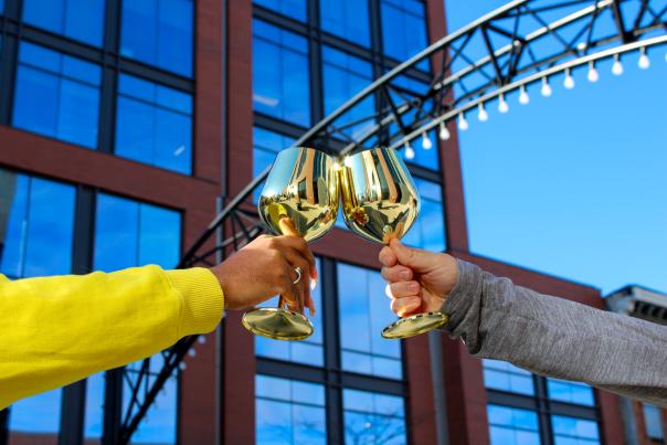 Two golden goblets shine in the sun under a Short North arch