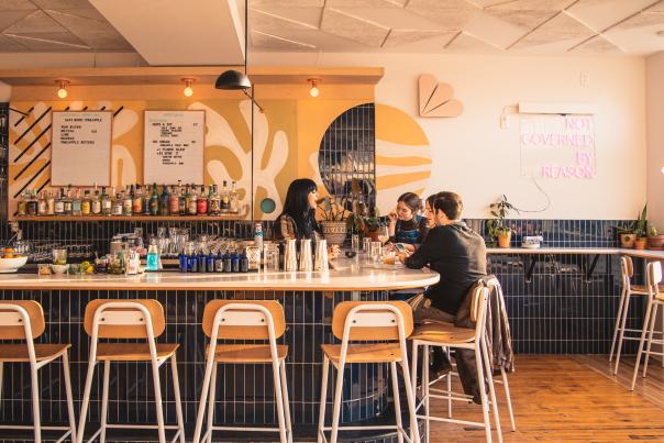 Bartender chats with two patrons on the other side of the bar