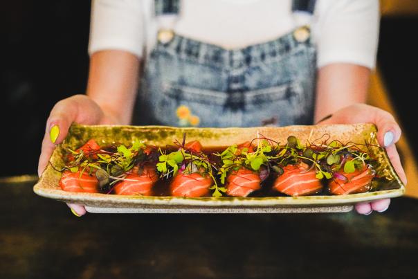 A person holding a sashimi platter at Domo Sushi Kitchen and Bar