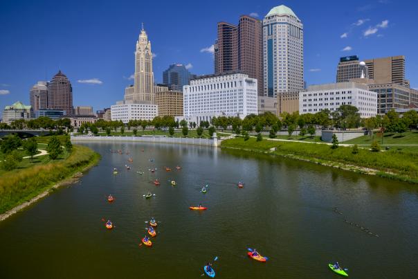 Kayakers float on the Scioto River with the Columbus skyline in the background