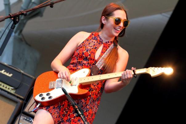 Musician Angela Perley playing guitar and smiling on stage during concert
