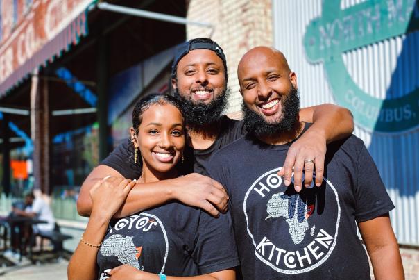 Three Hoyo's Kitchen workers hugging and smiling