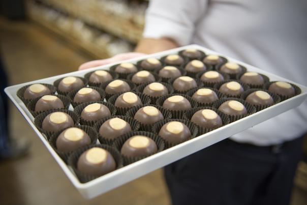 A woman's hand holds a tray of buckeye candies