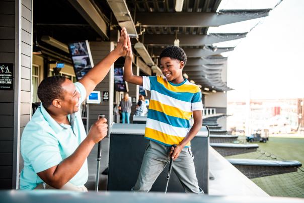 Father and son giving each other a "high five" at Topgolf