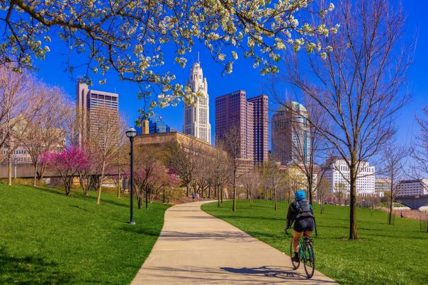 A photo of spring in downtown Columbus featuring a bike rider along the Scioto Mile