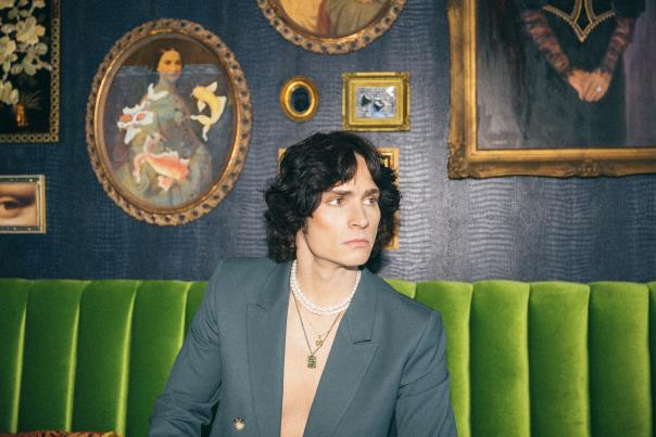 A picture of Spencer Sutherland seated on a green couch.