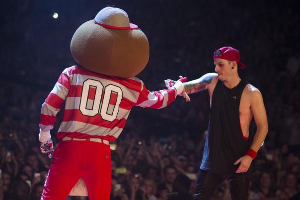 An image of 21 Pilots, Josh Dun shaking hands with Brutus Buckeye on stage