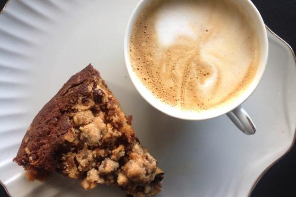 Top-down shot of scone on plate next to mug of foamy coffee from Bexley Coffee Shop